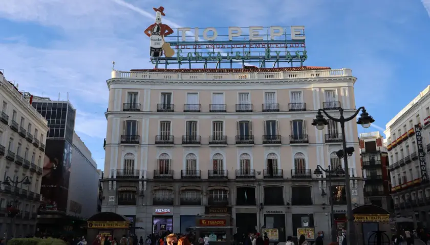 Edificio emblemático en la Puerta del Sol, Madrid. Ideal para saber qué ver en Madrid en un día, con el cartel de Tío Pepe y gente paseando.