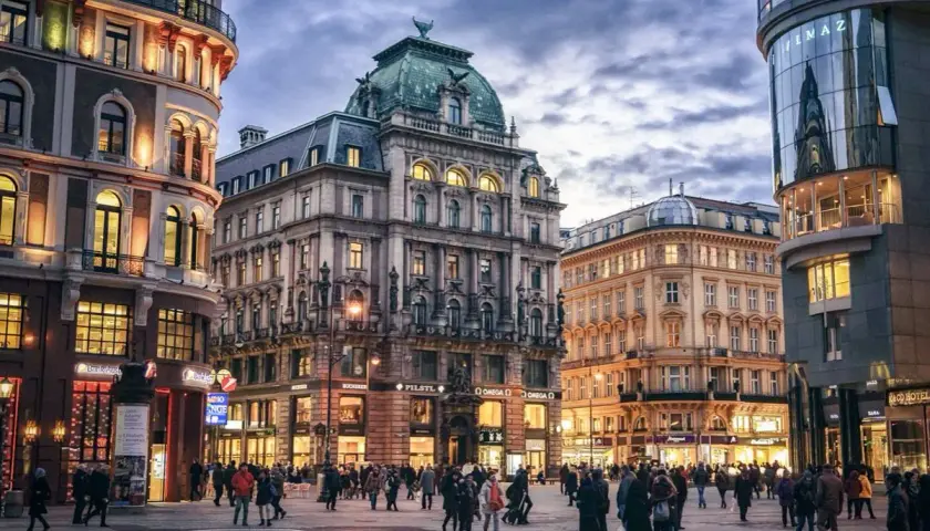 Gente paseando por una plaza en Viena, con edificios históricos y modernos. Ideal para un **free tour Viena**.