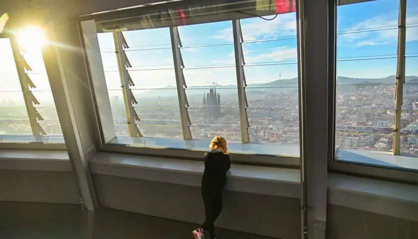 Niña contempla la Sagrada Familia desde el mirador Torre Glòries. El sol ilumina la ciudad.