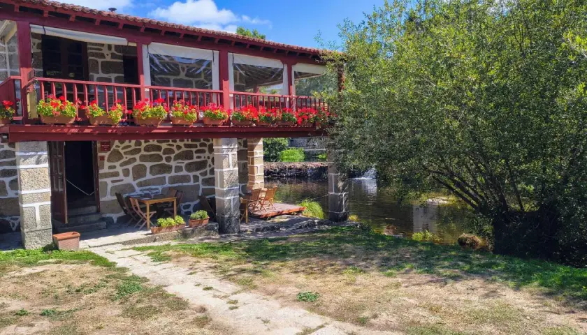 Casa rural con balcón florido y río. Un lugar idílico para descubrir qué ver en Allariz y disfrutar de la naturaleza.