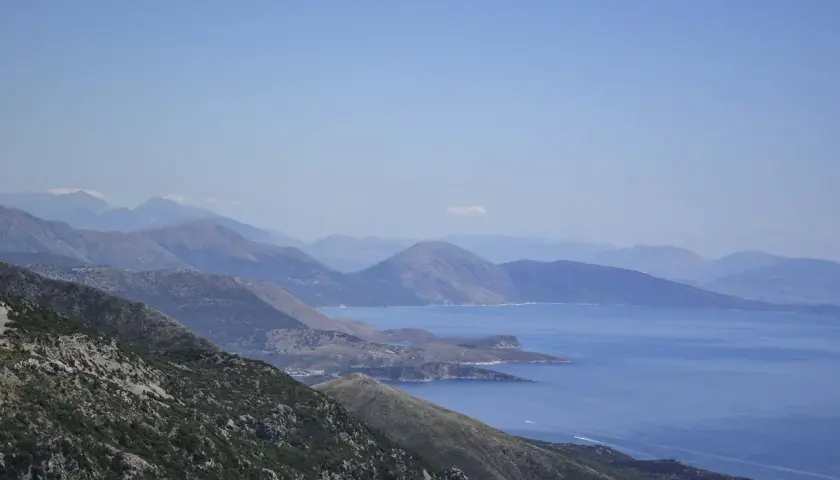 Paisaje montañoso con el mar azul al fondo, ideal para viajar a Albania y disfrutar de vistas espectaculares.