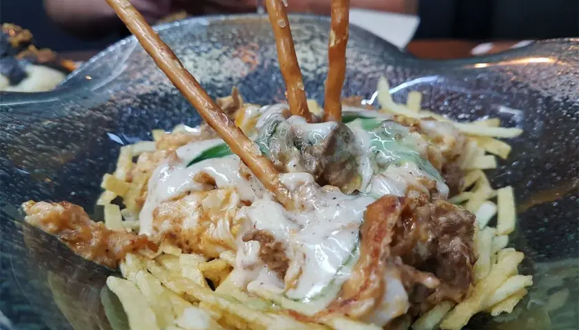 Un plato con patatas fritas, carne y palitos de pretzel. ¡Una idea de dónde comer en Cádiz!