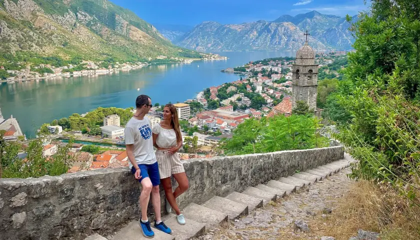 Pareja disfrutando de la vista panorámica de la bahía y la ciudad de Kotor, un destino ideal para viajar a Montenegro.