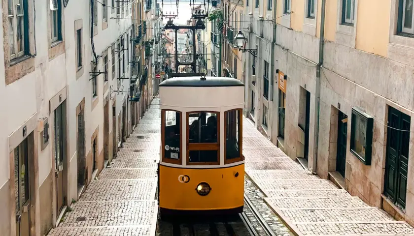 Tranvía amarillo subiendo una calle empedrada en Lisboa. ¡Imprescindible que ver en Lisboa en 4 días!