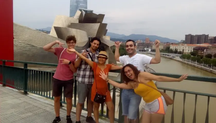 Grupo de amigos disfrutando de un free tour Bilbao, posando con el icónico Museo Guggenheim de fondo.