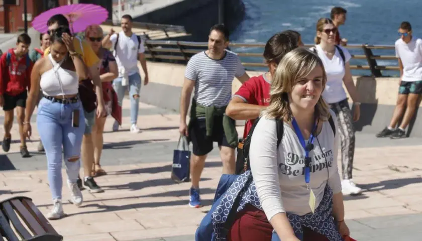 Un grupo de turistas participa en un free tour Gijón, disfrutando del paseo marítimo bajo un sol radiante.