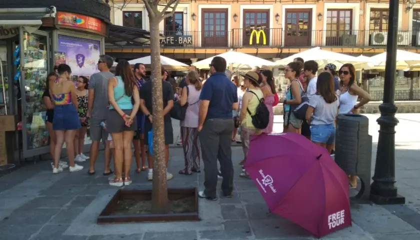 Grupo de turistas esperando un free tour a Toledo. Un paraguas morado con el logo de "Free Tour Toledo" está en primer plano.