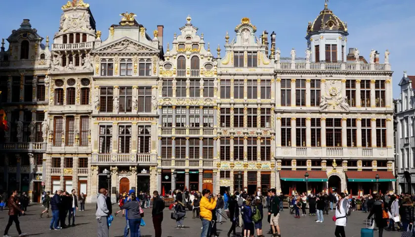 Gente paseando por la Grand Place de Bruselas, admirando la arquitectura dorada. Un lugar perfecto para viajar a Bruselas y capturar recuerdos.