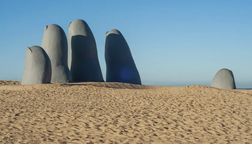 Escultura de una mano emergiendo de la arena en Punta del Este. Un imperdible que ver en Uruguay.
