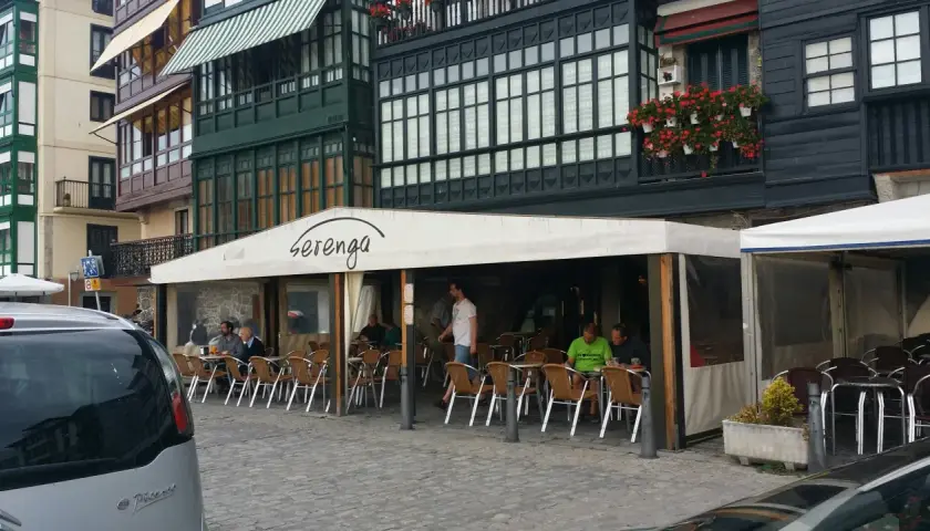 Gente disfrutando de un día soleado para comer en Lekeitio, sentados en las mesas de un restaurante con toldo blanco.