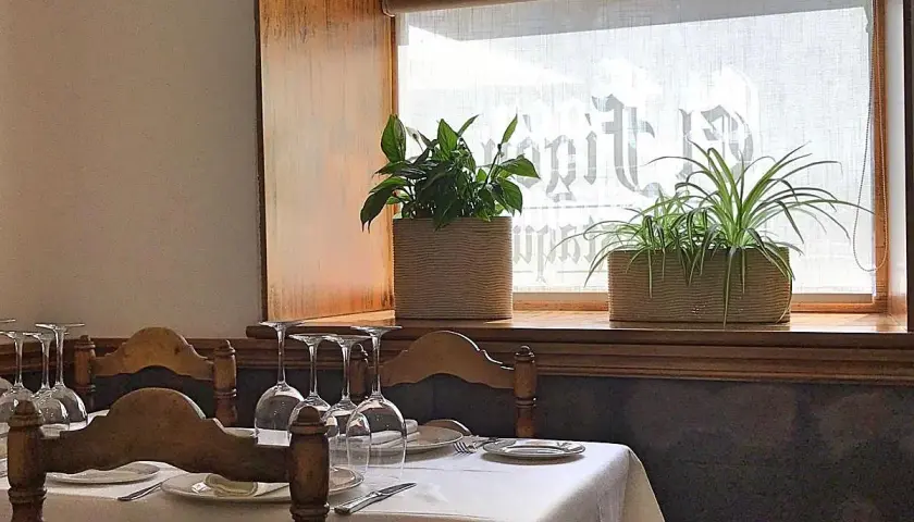Mesa puesta con copas y plantas en ventana, ideal para saber donde comer en Cáceres.