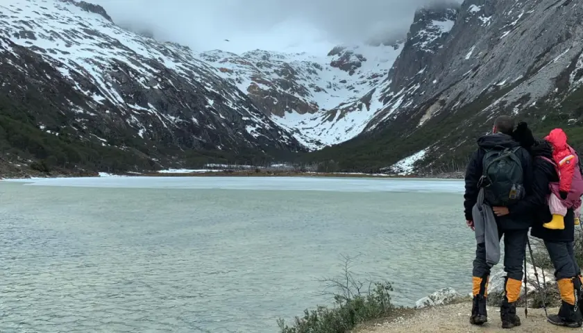 Dos personas admiran un lago helado y montañas nevadas, un paisaje impresionante de lo que ver en Argentina.