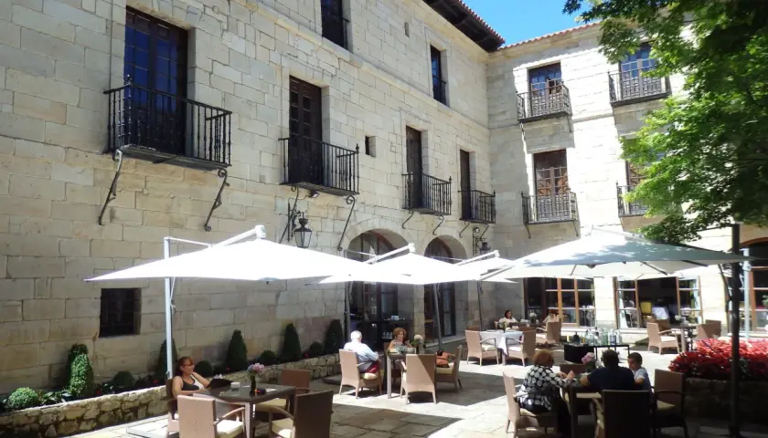 Disfruta de un día soleado donde comer en Santillana del Mar, con mesas al aire libre bajo sombrillas blancas, rodeado de arquitectura de piedra.
