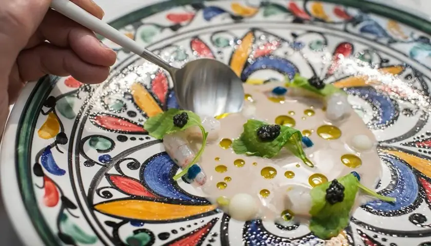 Delicioso plato de mariscos con caviar y hojas verdes, servido en una vajilla colorida. Una excelente opción para saber donde comer en Córdoba.