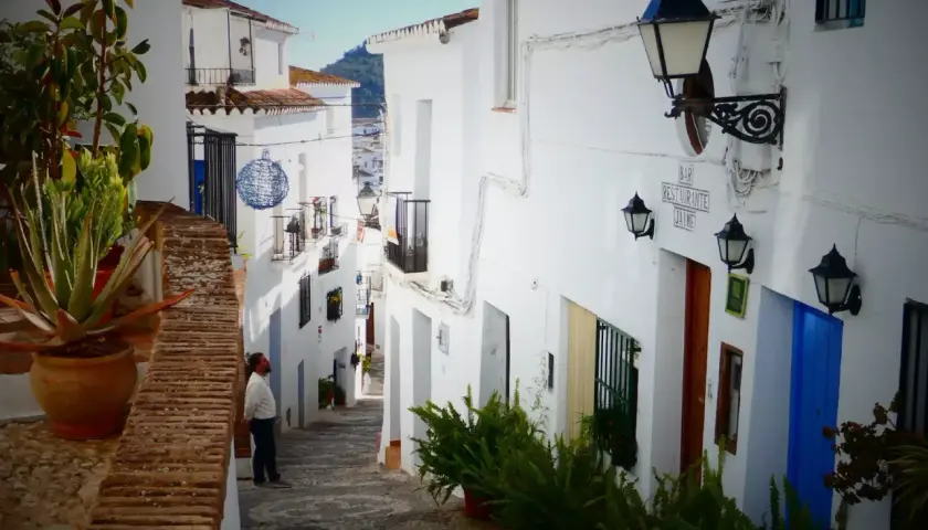 Hombre mira callejuela blanca en Frigiliana. Aquí puedes encontrar dónde comer en Frigiliana, con un bar y restaurante.