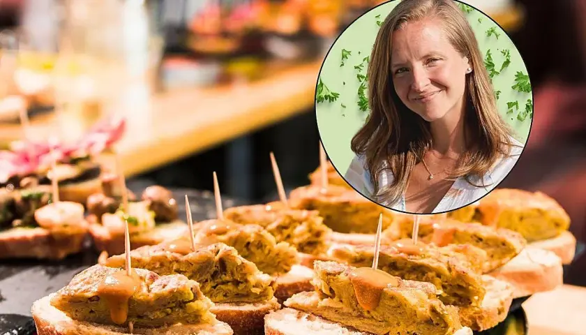 Una mujer sonríe mientras disfruta de deliciosos pintxos, una experiencia culinaria para comer en San Sebastián.