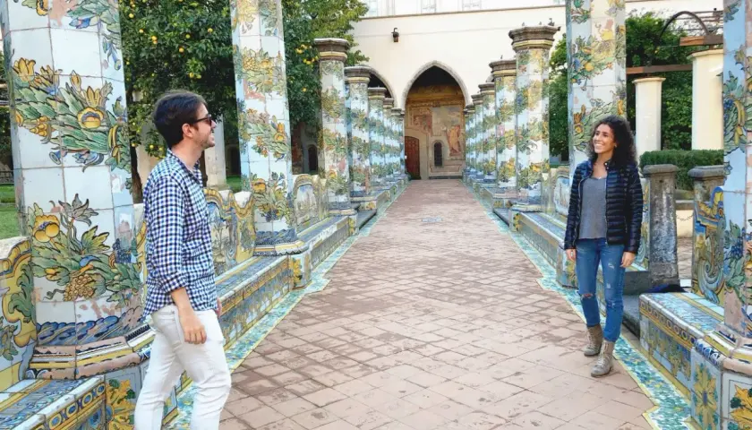 Pareja admira la cerámica de mayólica en un claustro, ideal para ver en Nápoles en 1 día.
