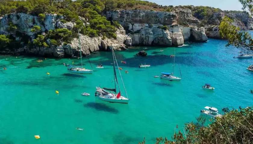 Calas turquesas y veleros anclados, ideal para saber qué ver en Menorca en 3 días. Disfruta de un día perfecto en este paraíso.