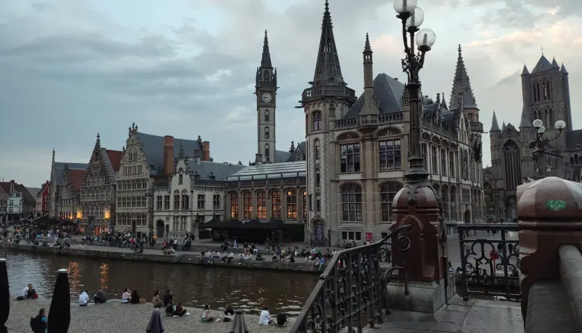 Gante, Bélgica: edificios históricos junto al río, gente sentada en la orilla. Un lugar ideal que ver en Bélgica.