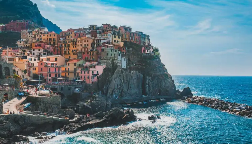 Pueblo costero italiano con casas coloridas en acantilados. Ideal para excursiones desde Milán.