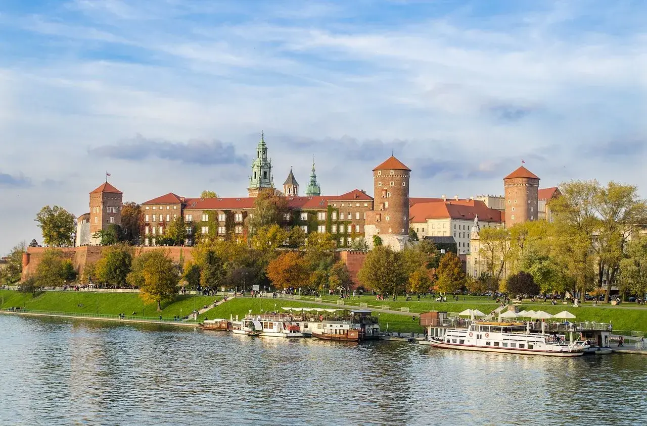 Castillo de Wawel sobre el río Vístula, ideal para excursiones en Krakow. Barcos turísticos esperan a los visitantes.