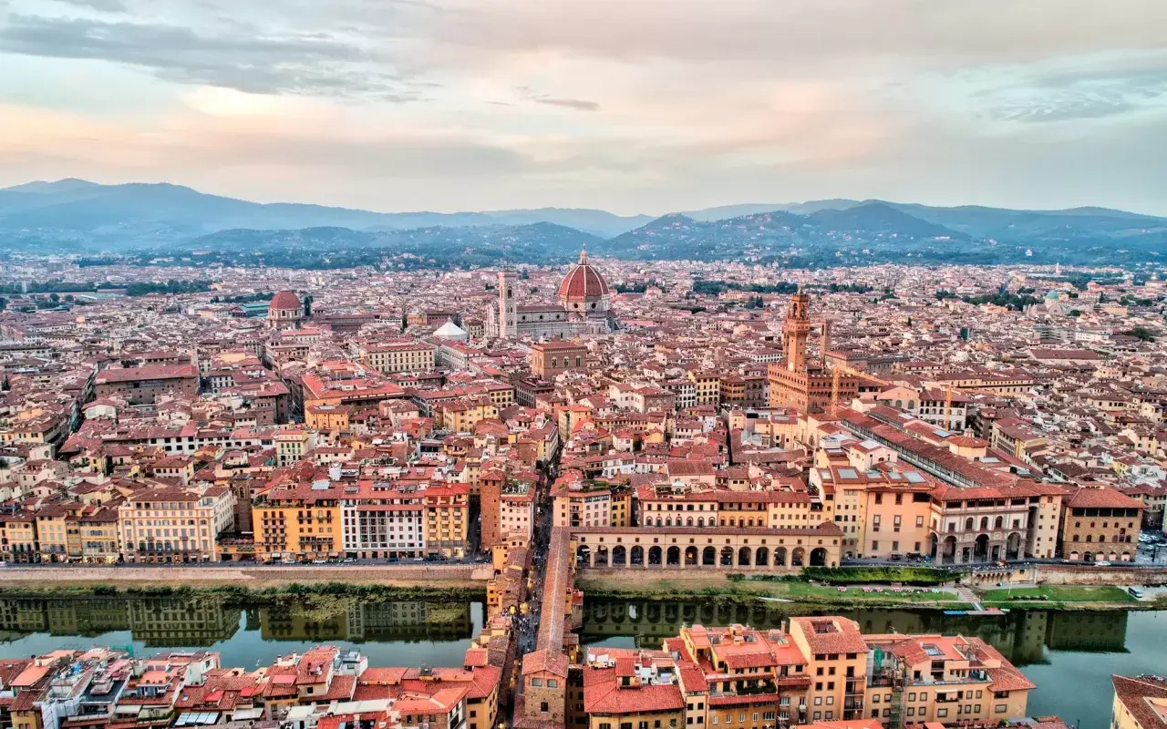 Vista panorámica de Florencia al atardecer, con la cúpula del Duomo y el Ponte Vecchio. Ideal para un **free tour Florencia**.