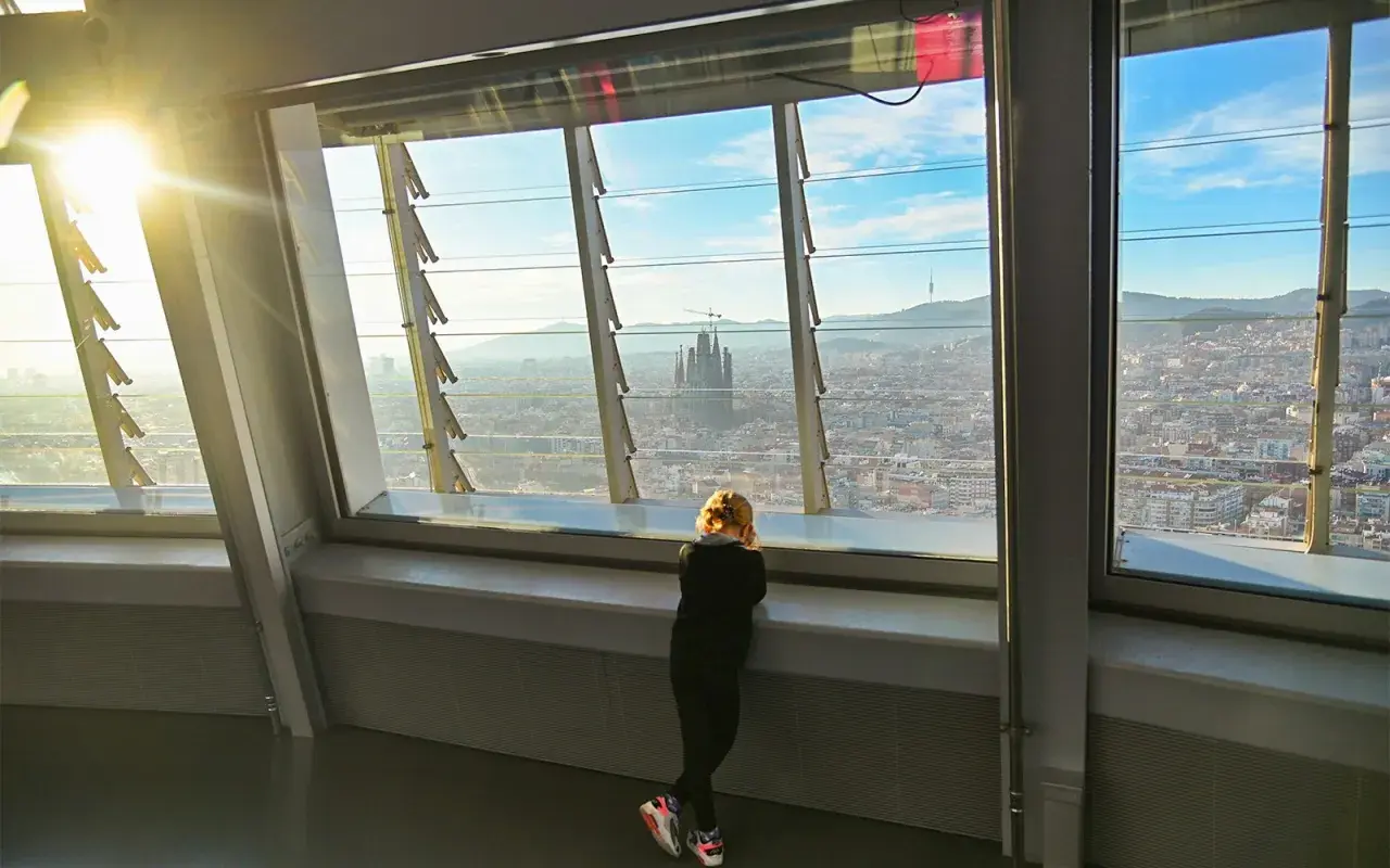Niña contempla la Sagrada Familia desde el mirador Torre Glòries. El sol ilumina la ciudad.