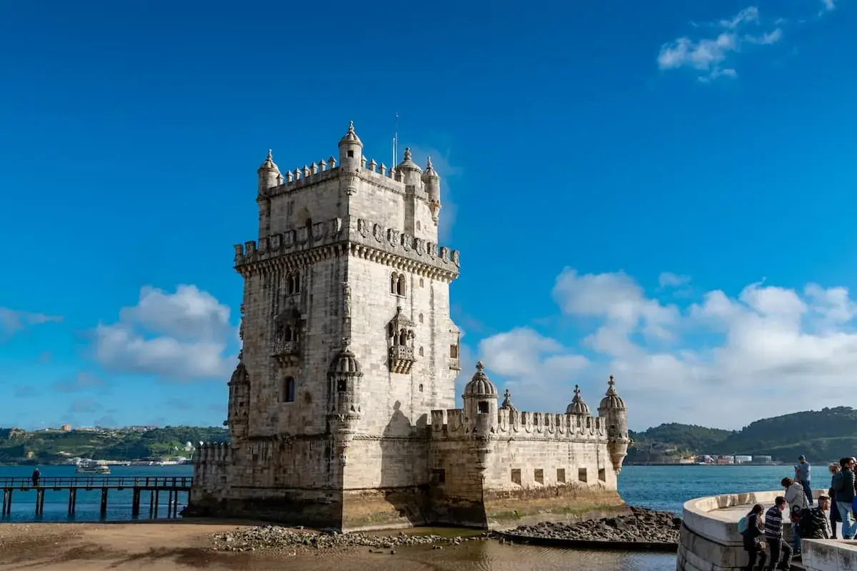 Torre de Belém, un sitio histórico perfecto para un free tour Lisboa. El cielo azul y el agua reflejan su belleza.