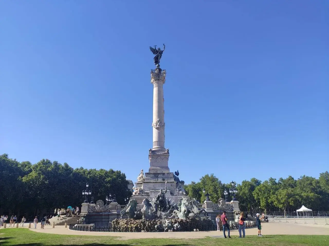 Monumento de la Gironda en Burdeos, ideal para un free tour Burdeos. Gente paseando bajo el cielo azul.