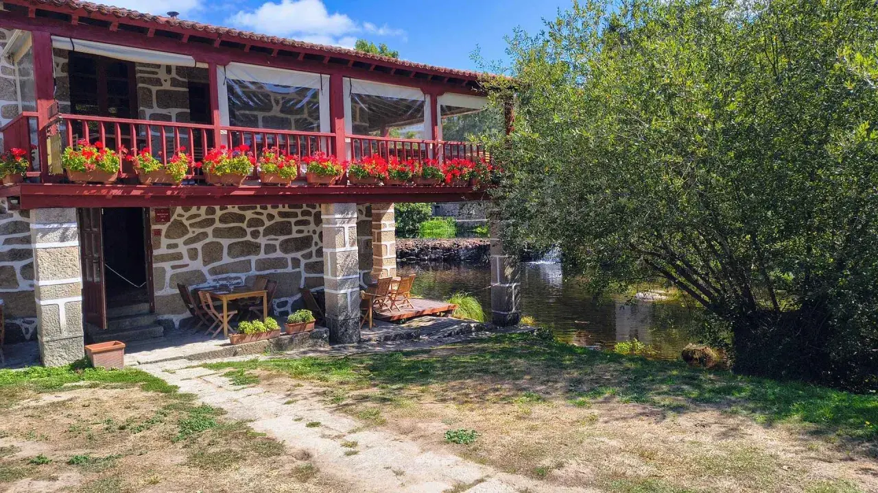 Casa rural con balcón florido y río. Un lugar idílico para descubrir qué ver en Allariz y disfrutar de la naturaleza.