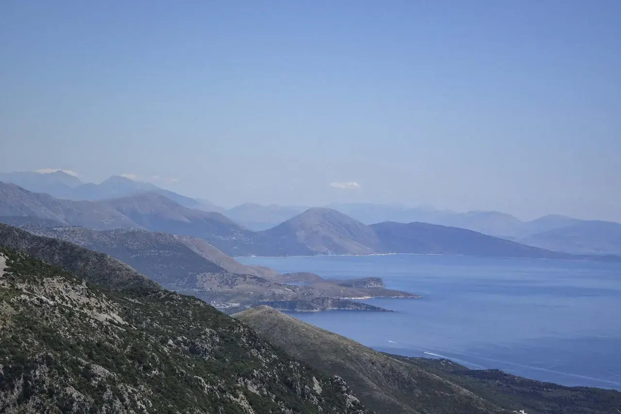 Paisaje montañoso con el mar azul al fondo, ideal para viajar a Albania y disfrutar de vistas espectaculares.