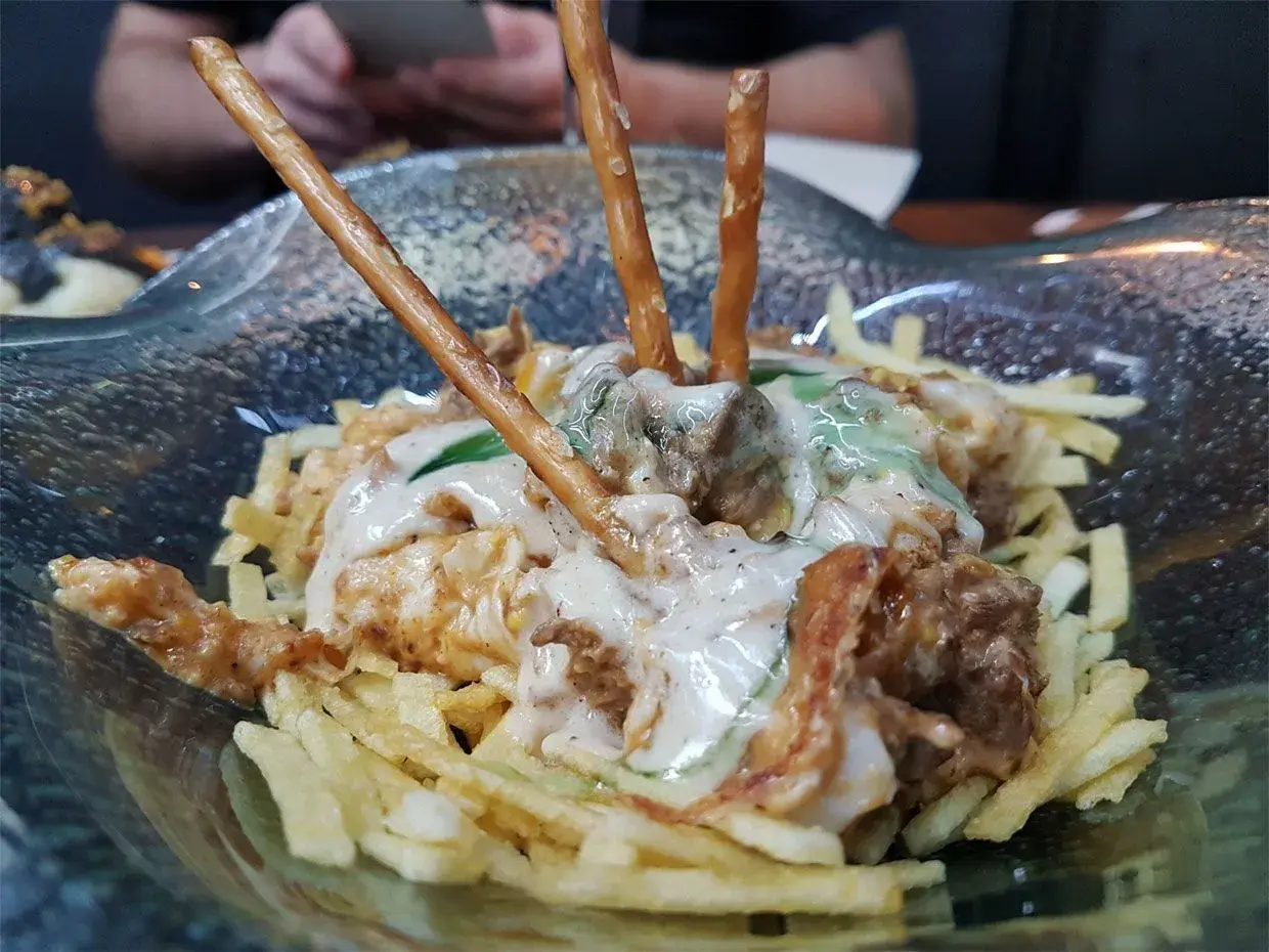 Un plato con patatas fritas, carne y palitos de pretzel. ¡Una idea de dónde comer en Cádiz!