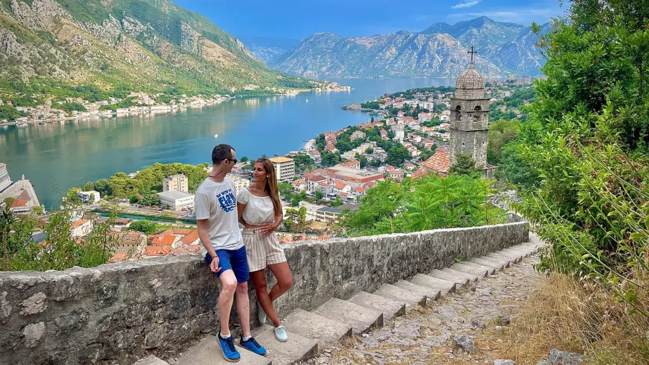 Pareja disfrutando de la vista panorámica de la bahía y la ciudad de Kotor, un destino ideal para viajar a Montenegro.