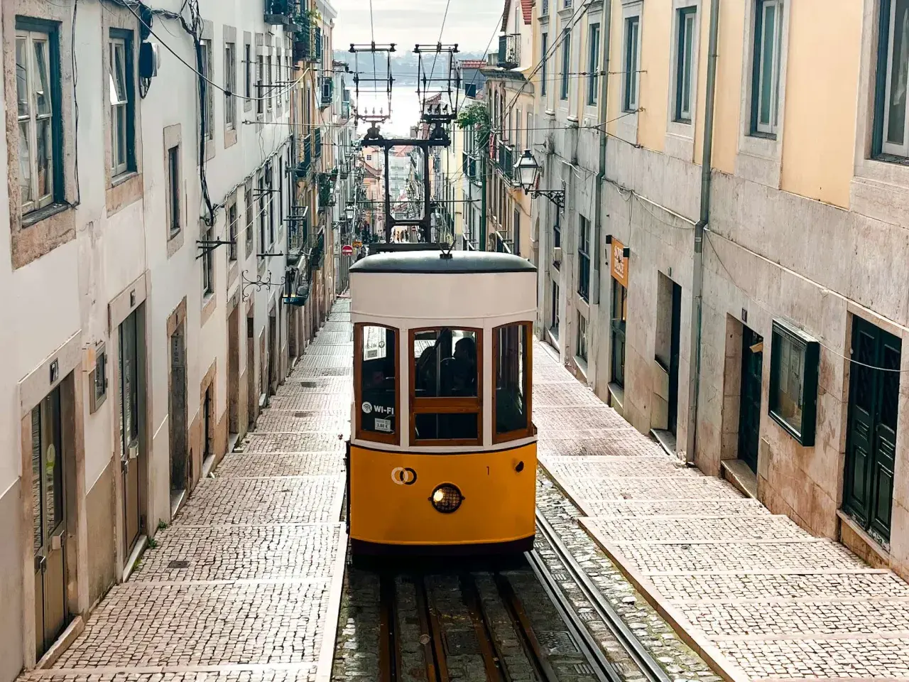 Tranvía amarillo subiendo una calle empedrada en Lisboa. ¡Imprescindible que ver en Lisboa en 4 días!