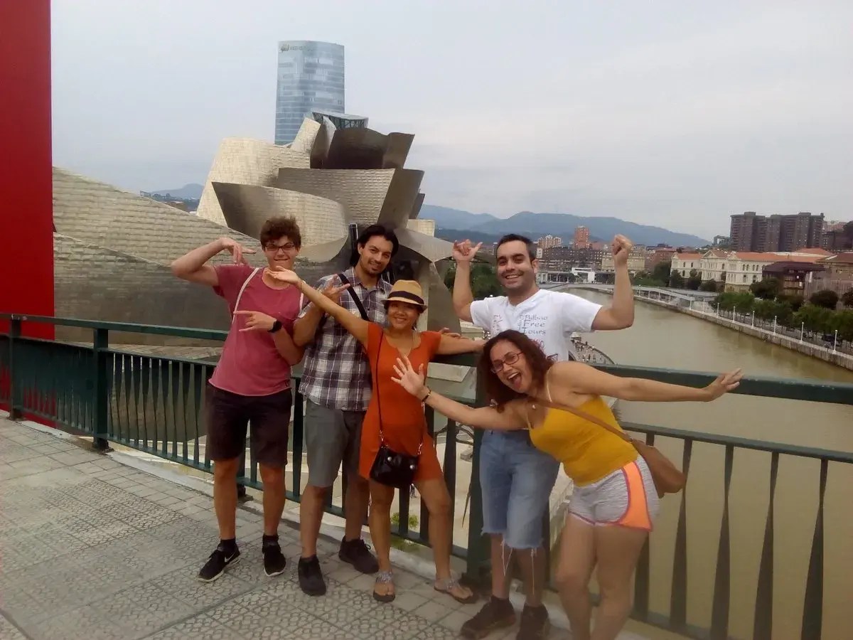 Grupo de amigos disfrutando de un free tour Bilbao, posando con el icónico Museo Guggenheim de fondo.