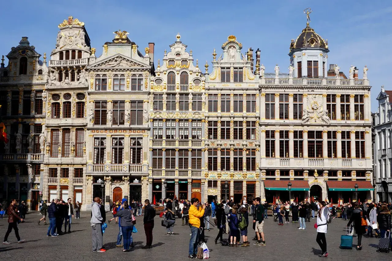 Gente paseando por la Grand Place de Bruselas, admirando la arquitectura dorada. Un lugar perfecto para viajar a Bruselas y capturar recuerdos.