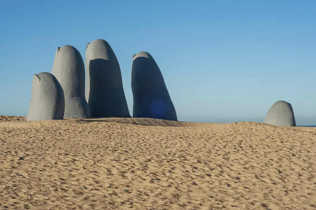 Escultura de una mano emergiendo de la arena en Punta del Este. Un imperdible que ver en Uruguay.