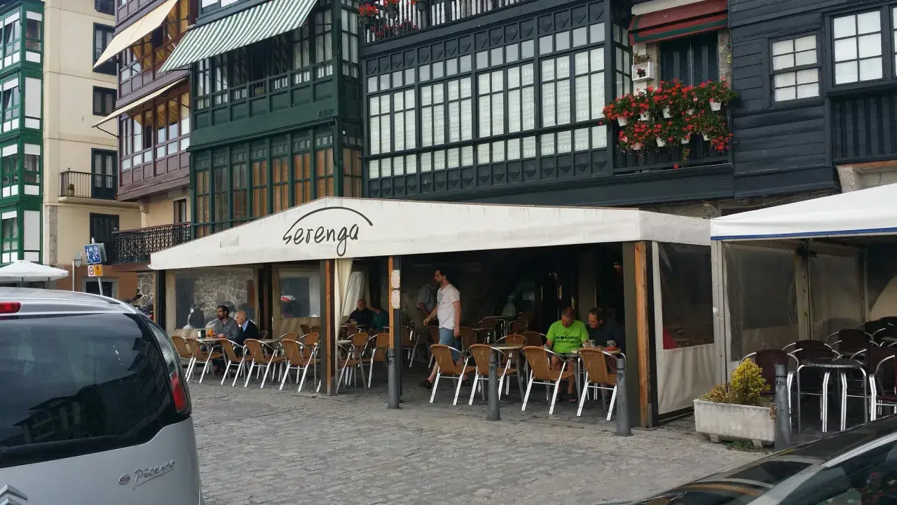Gente disfrutando de un día soleado para comer en Lekeitio, sentados en las mesas de un restaurante con toldo blanco.