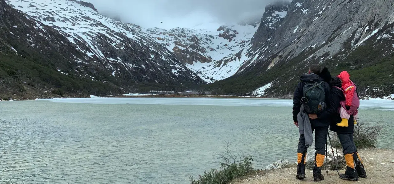 Dos personas admiran un lago helado y montañas nevadas, un paisaje impresionante de lo que ver en Argentina.