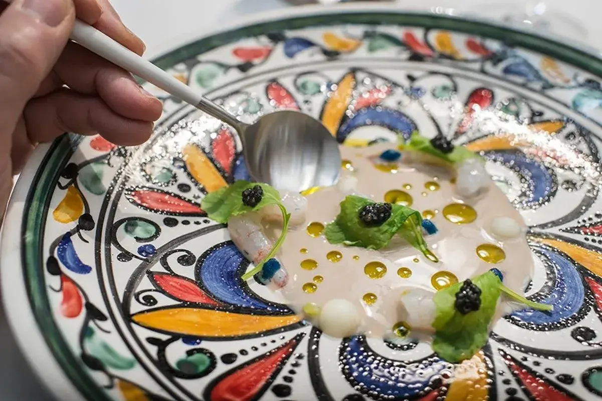 Delicioso plato de mariscos con caviar y hojas verdes, servido en una vajilla colorida. Una excelente opción para saber donde comer en Córdoba.