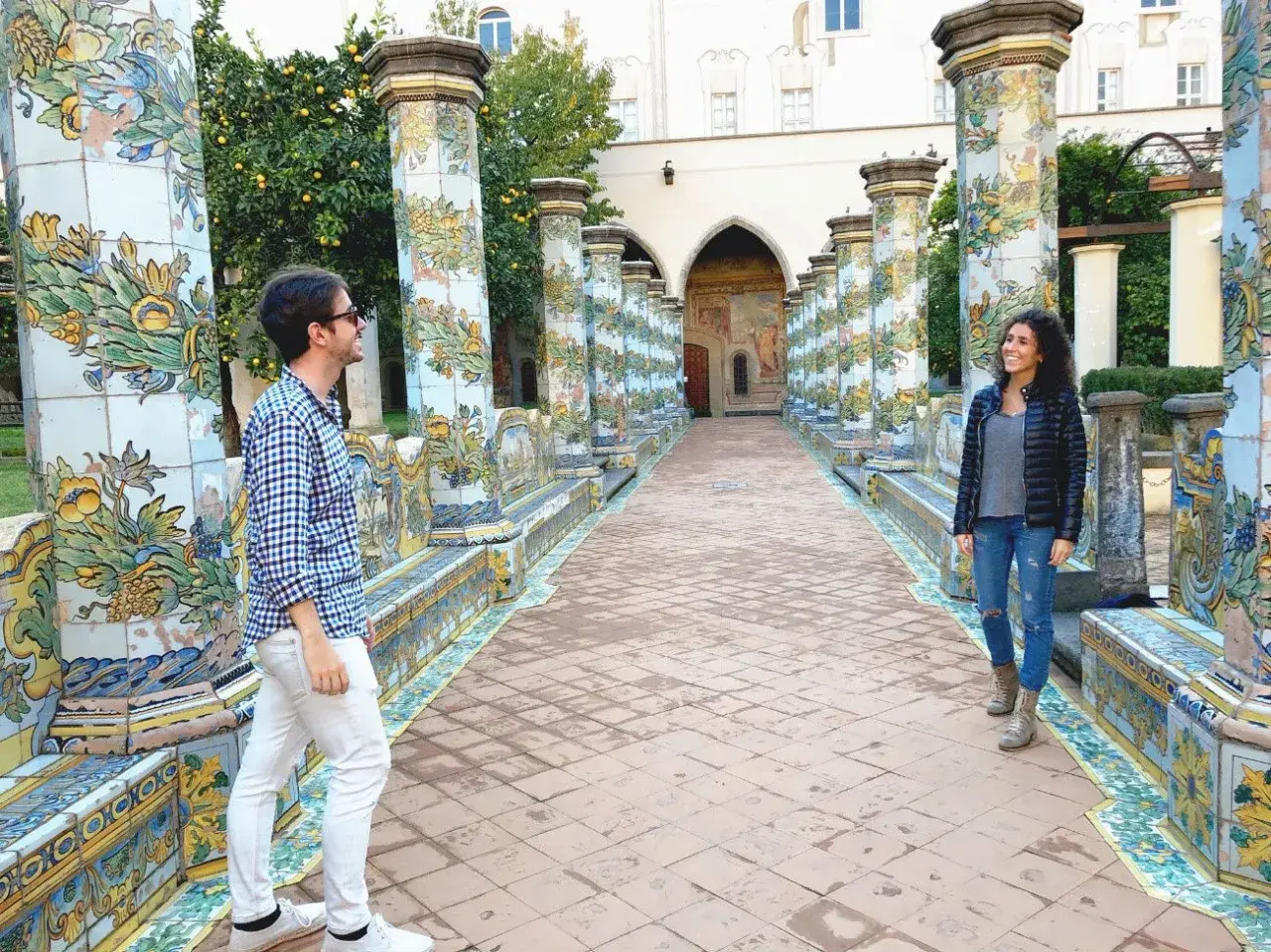 Pareja admira la cerámica de mayólica en un claustro, ideal para ver en Nápoles en 1 día.