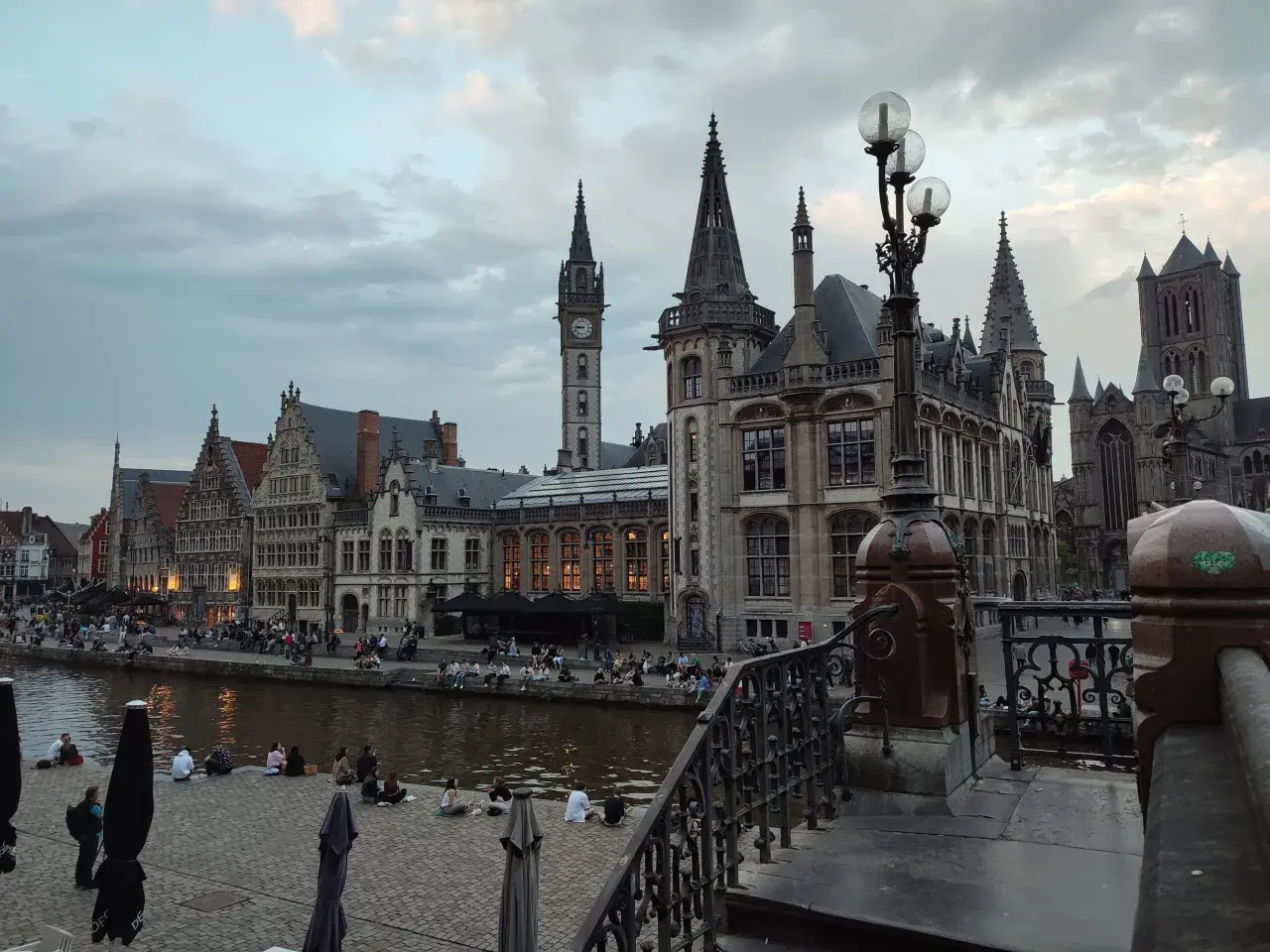 Gante, Bélgica: edificios históricos junto al río, gente sentada en la orilla. Un lugar ideal que ver en Bélgica.
