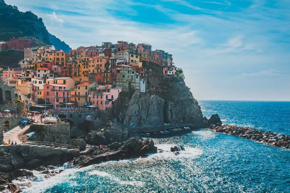 Pueblo costero italiano con casas coloridas en acantilados. Ideal para excursiones desde Milán.