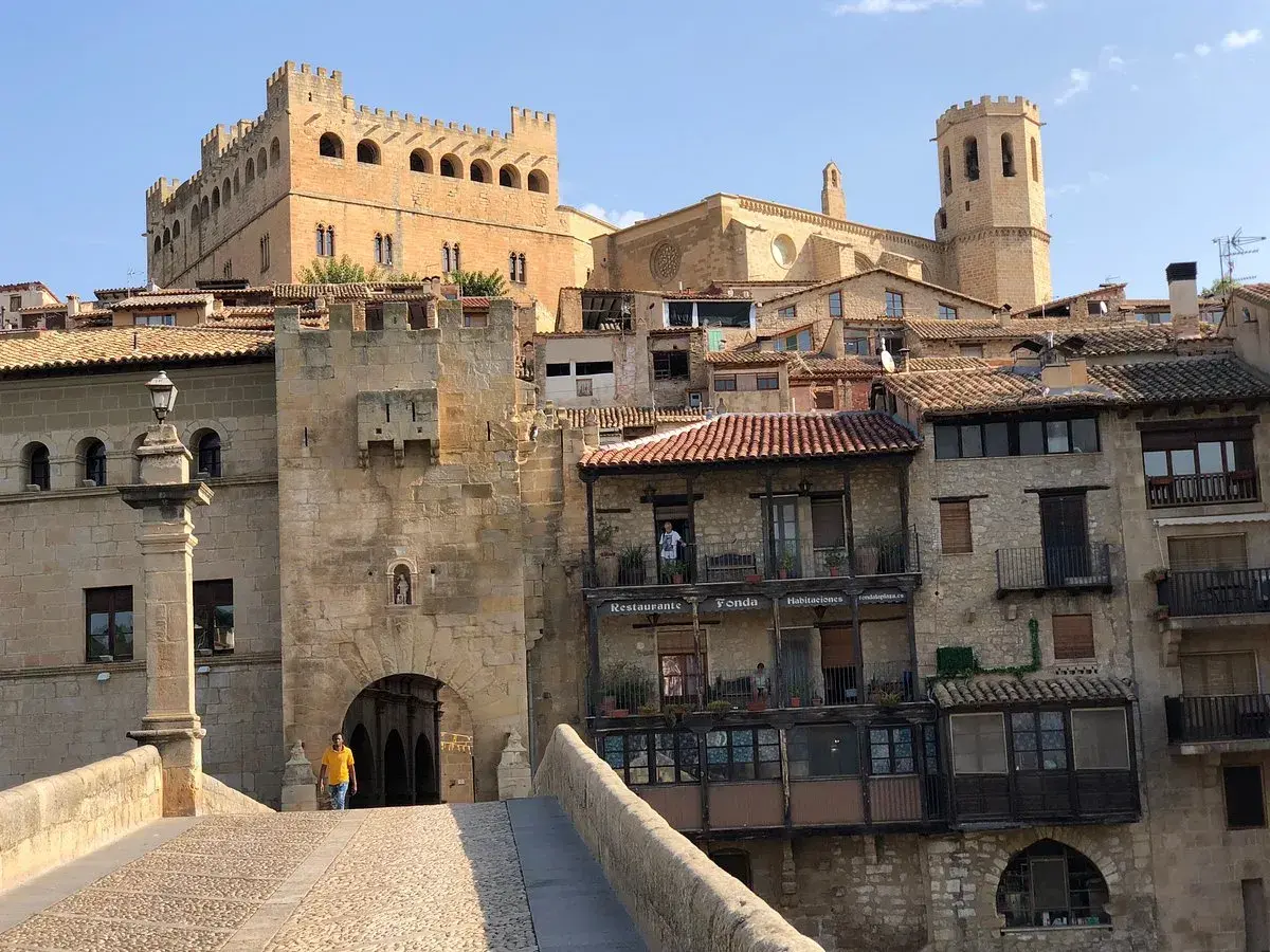 Un hombre cruza el puente hacia el castillo de Valderrobres, un lugar que ver para disfrutar de su arquitectura medieval y sus calles empedradas.