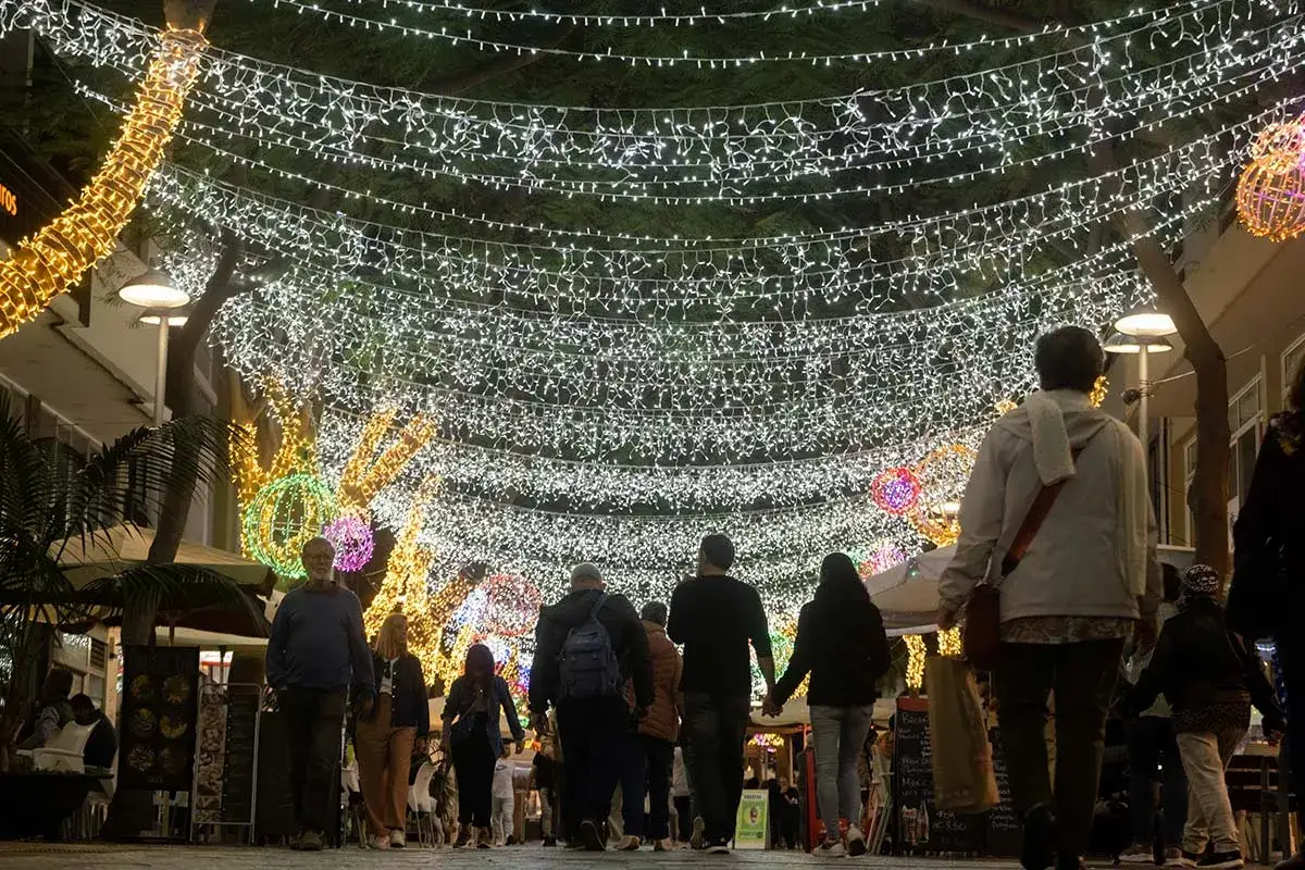 Gente pasea bajo luces navideñas en Santa Cruz de Tenerife. Un ambiente festivo ideal para decidir dónde comer en Santa Cruz de Tenerife.