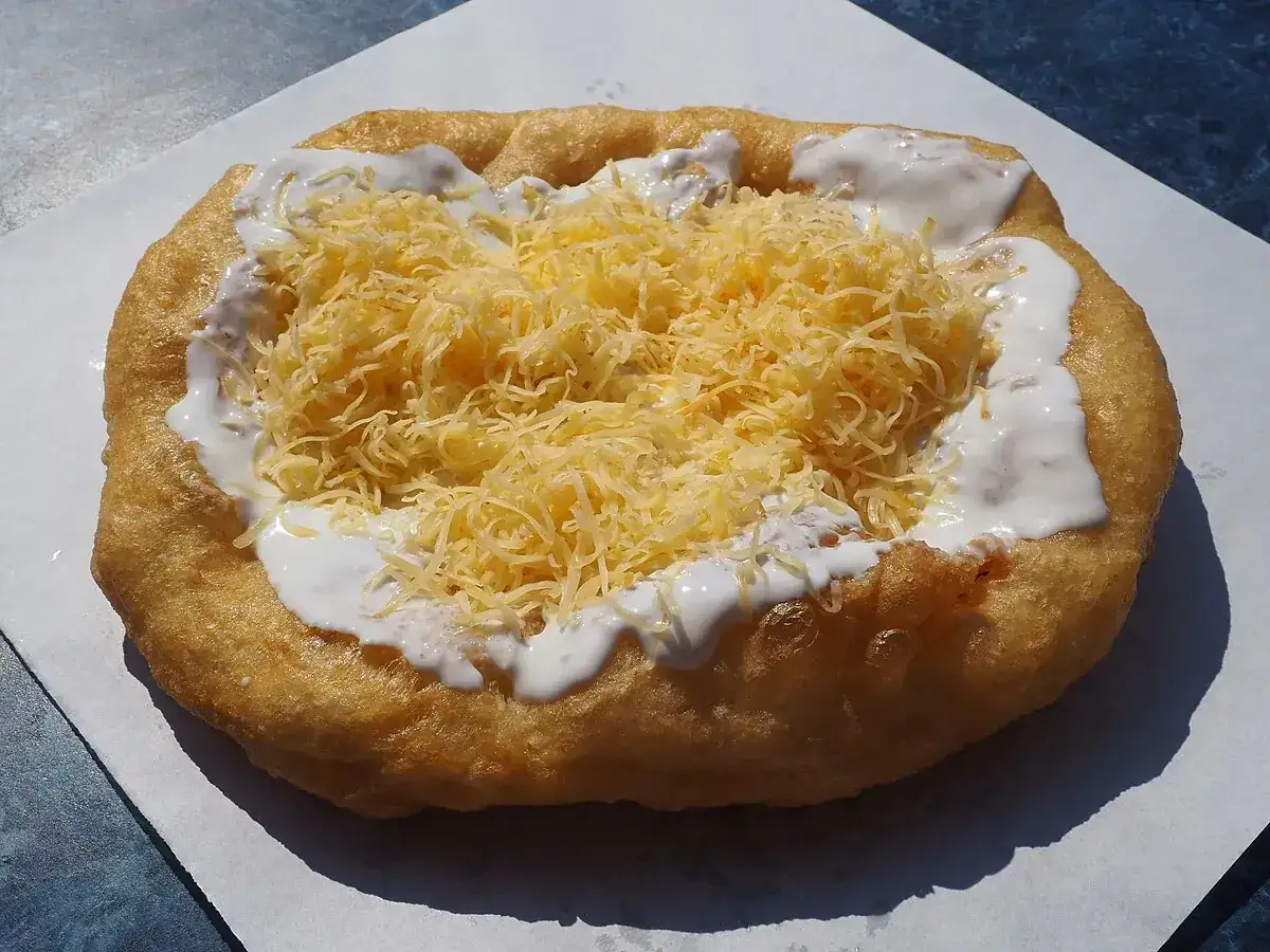 L&aacute;ngos, un delicioso bocado para comer en Budapest, cubierto con queso rallado y crema agria.