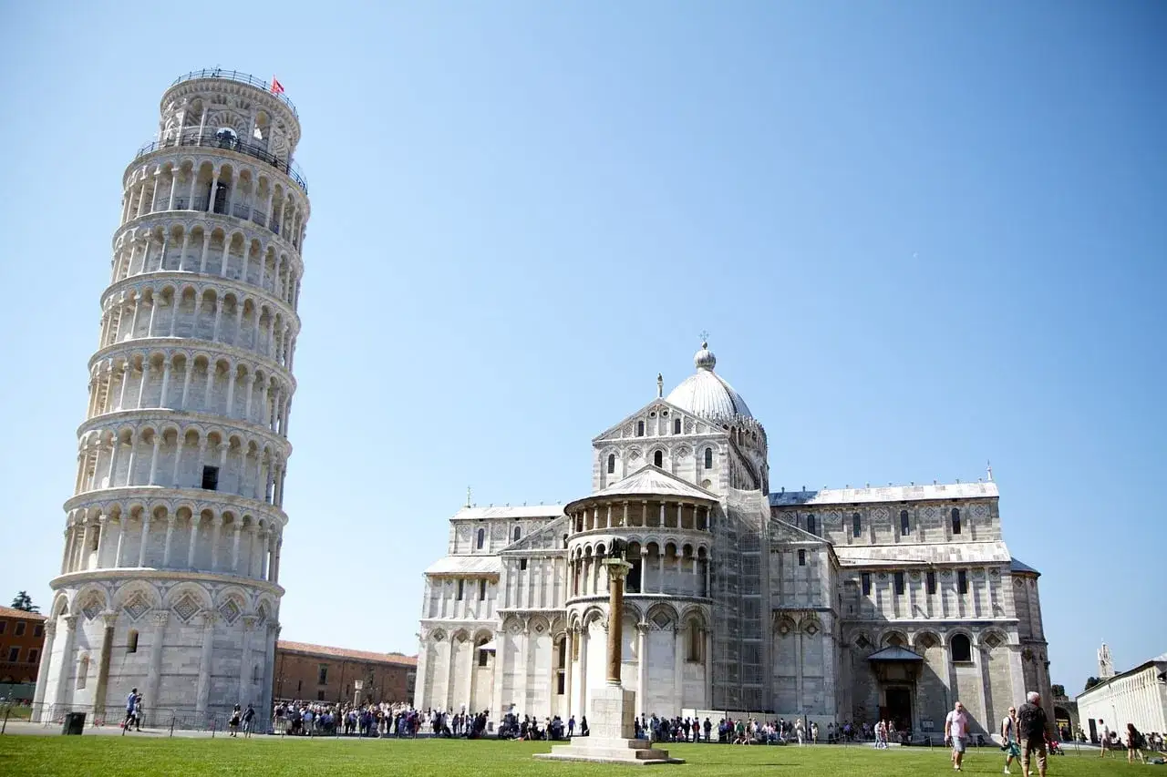 Torre de Pisa y la Catedral, icónicos monumentos de Italia, bajo un cielo azul.