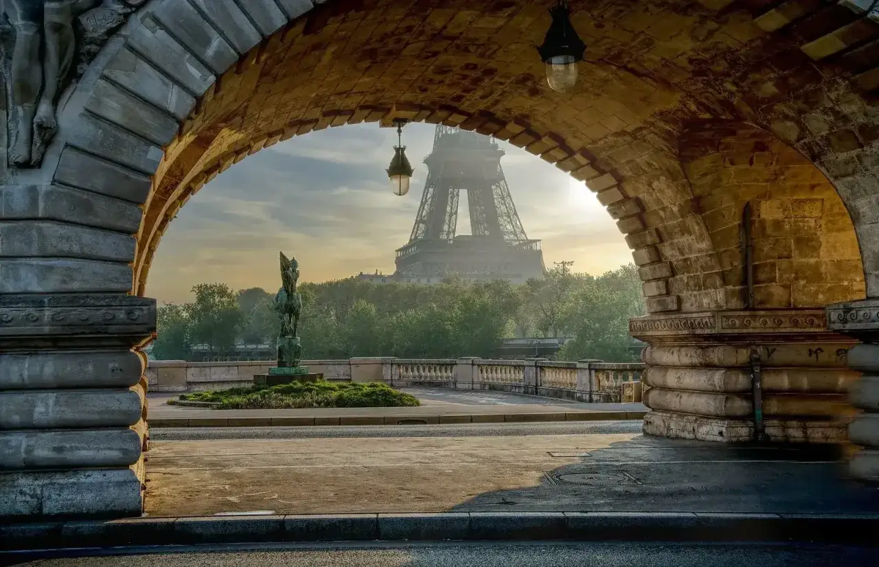 Arco de piedra con la Torre Eiffel al fondo, ideal para un free tour Paris.