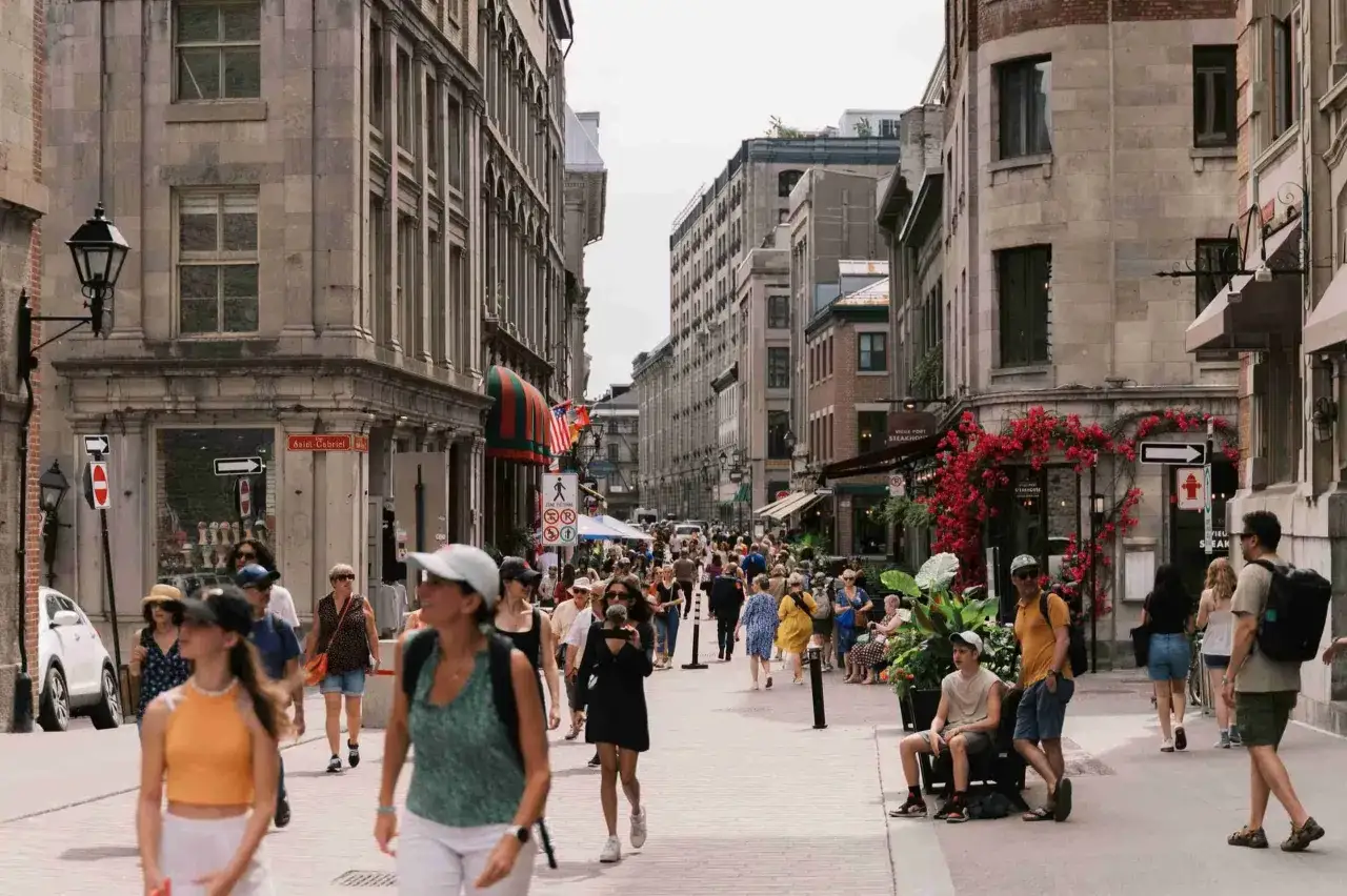 Gente paseando por una calle peatonal en Montreal, ideal para visitas guiadas. Edificios antiguos y ambiente vibrante.