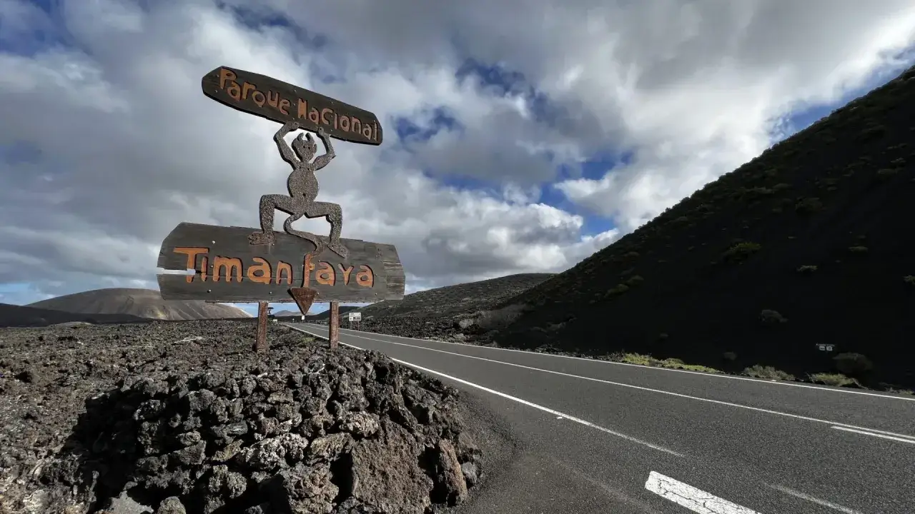 Cartel de Parque Nacional Timanfaya, ideal para tu plan de Lanzarote en 4 días. Paisaje volcánico y cielo nublado.